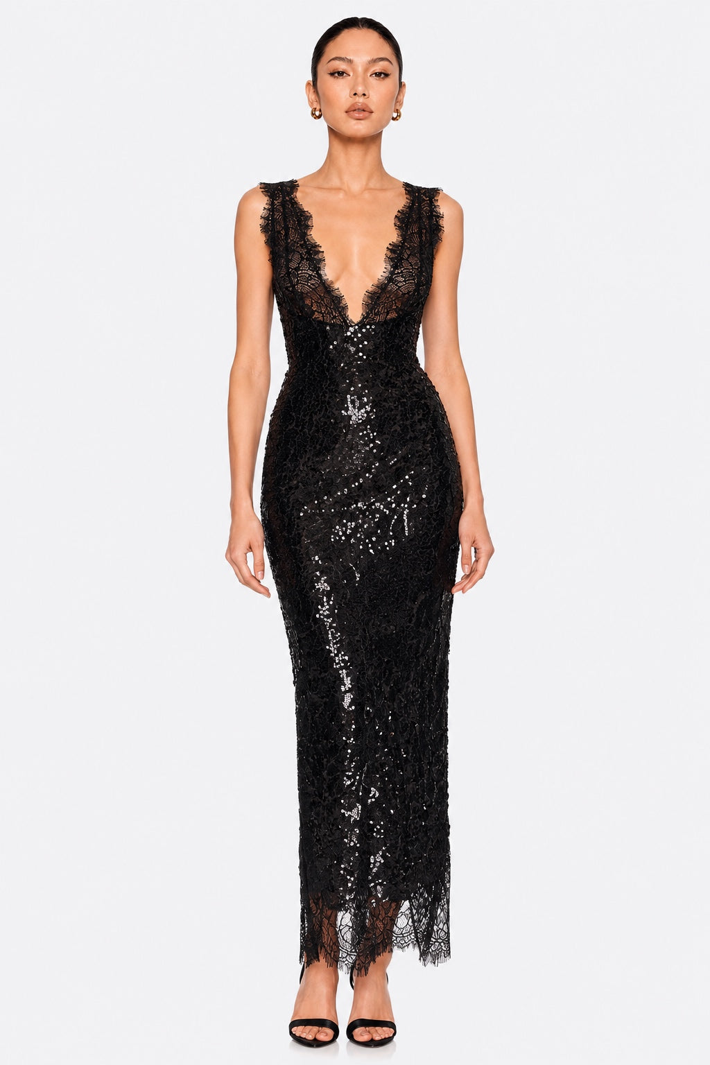 A model wearing a sleeveless black lace and sequin maxi dress with a deep V-neckline, photographed against a solid light gray background.