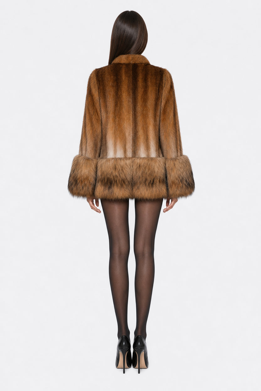 A model shown from the back wearing a brown fur coat with a wide collar and matching faux-fur hem, paired with black tights and black high heels, against a plain white background.