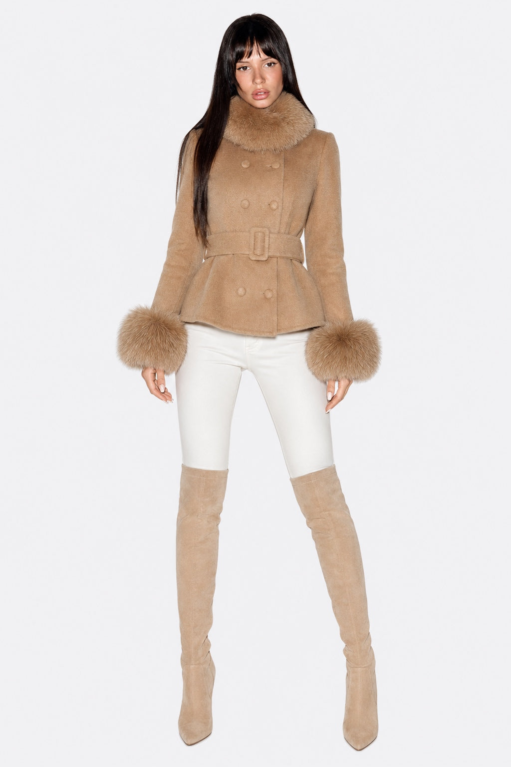A model wearing a camel-colored double-breasted coat with a faux-fur collar and cuffs, paired with white skinny pants and matching beige over-the-knee boots, against a plain white background.