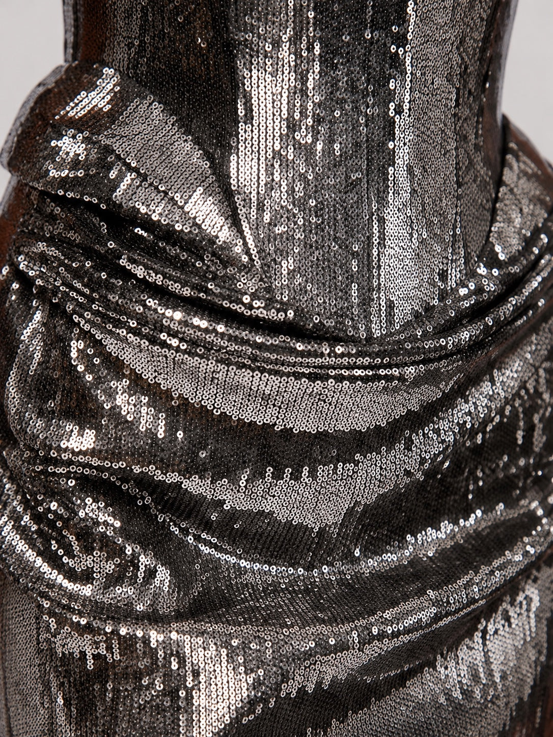 Close-up of a metallic silver sequined fabric with a draped, gathered texture.