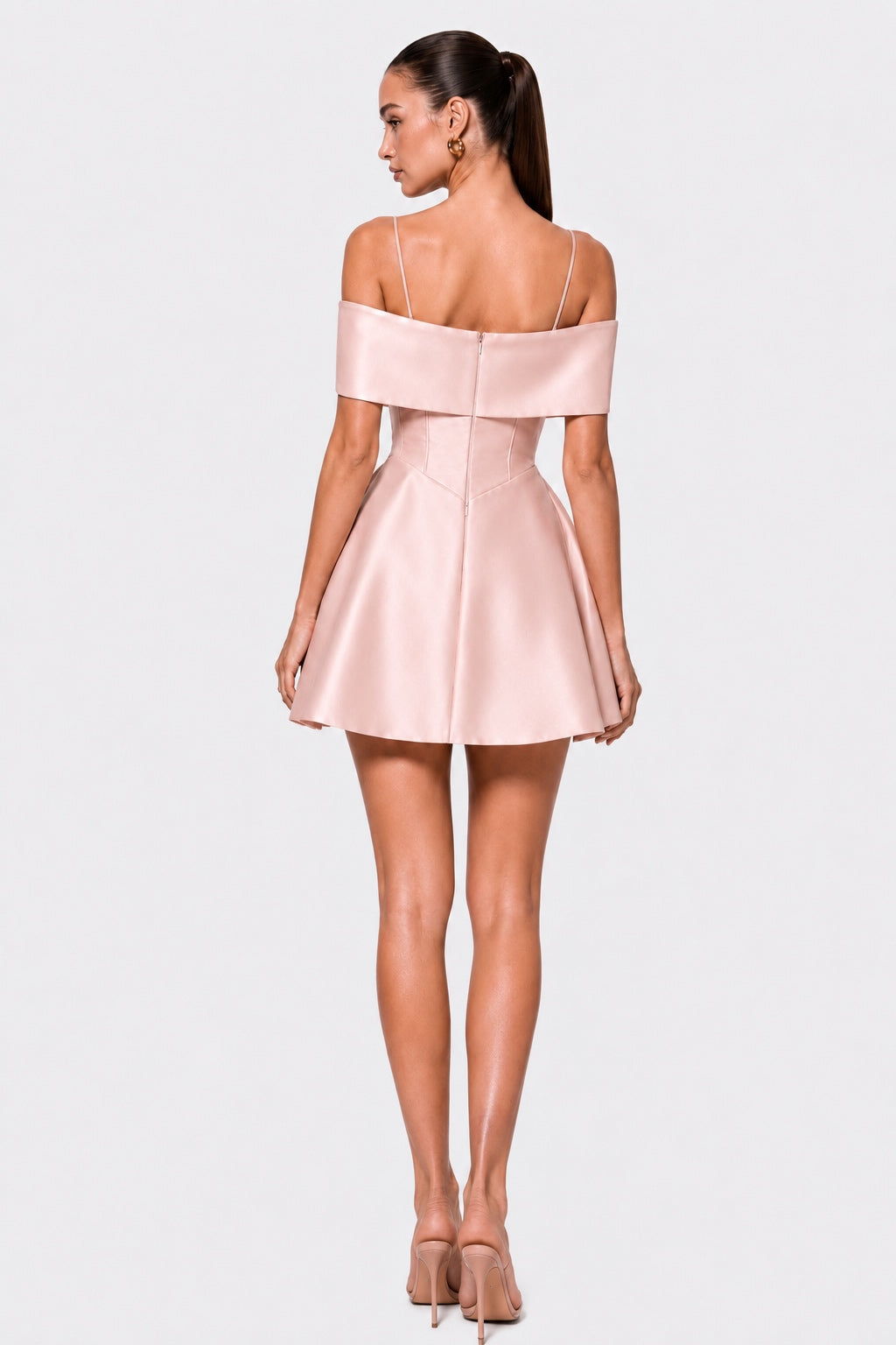 A woman modeling a short off-the-shoulder satin dress from the back, shown against a plain light gray studio background.
