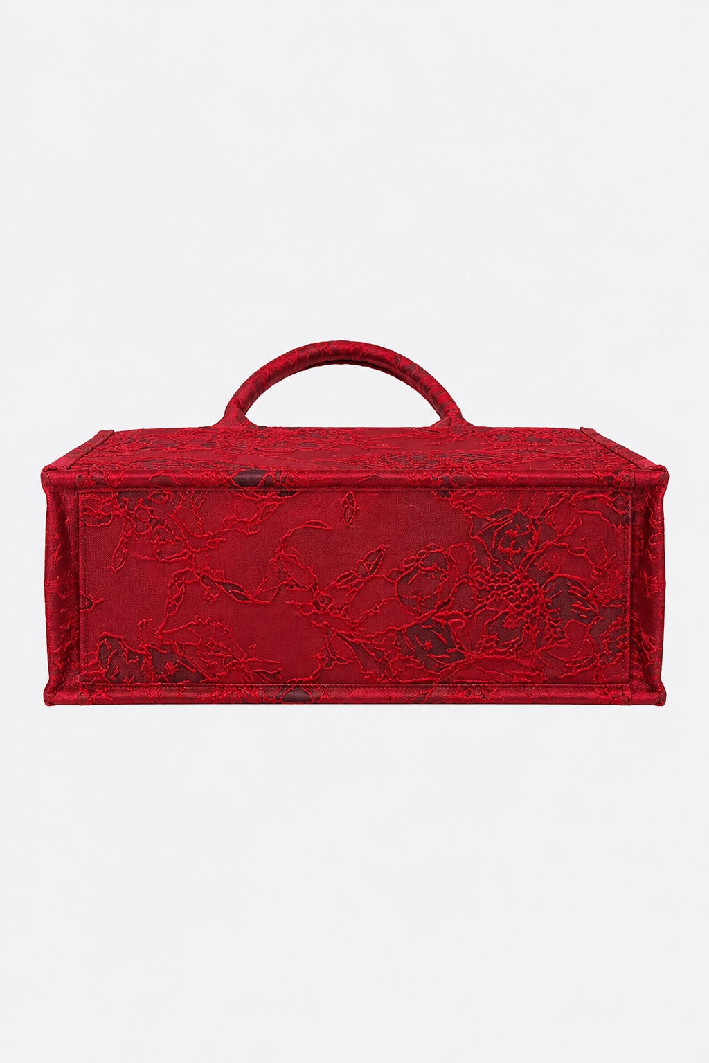 A red rectangular handbag with a top handle, featuring an embossed floral pattern on a textured red surface, shown against a plain light gray background.