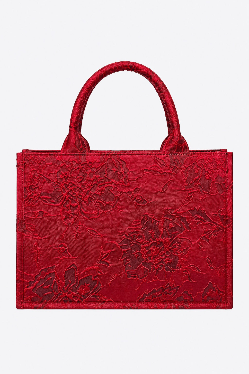 A red structured tote bag with floral embossed leather detailing and dual top handles, shown against a plain light gray background.