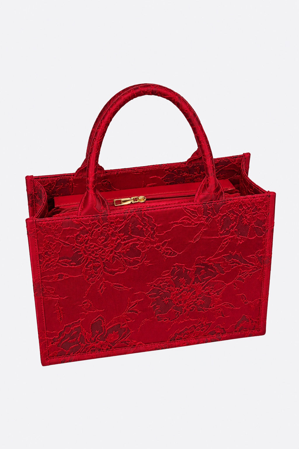 A red structured handbag with floral jacquard embroidery, dual top handles, and a gold zipper closure, shown against a light gray background.