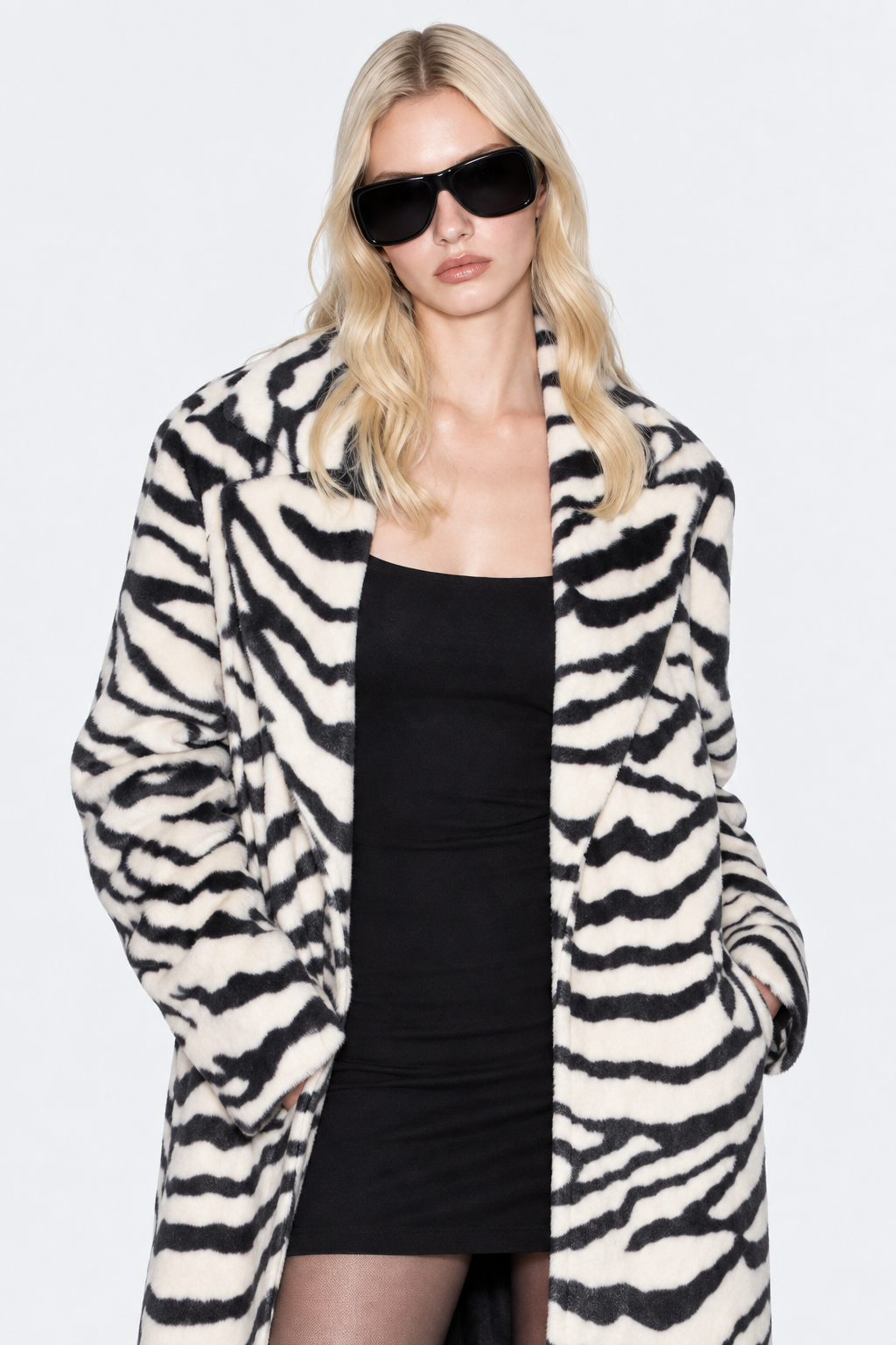 Closer front view of the zebra-print coat showing wide lapels, long sleeves and pockets.